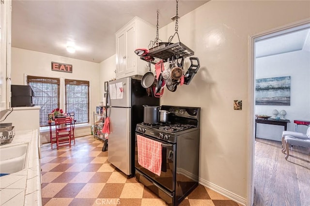 4912 Edgewood Pl, Los Angeles, CA 90019 - kitchen with gas stove, freestanding refrigerator, white cabinetry, baseboards, and light floors