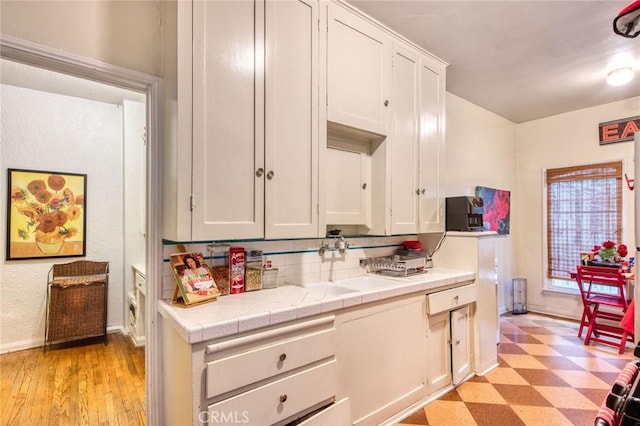 4912 Edgewood Pl, Los Angeles, CA 90019 - kitchen featuring tile countertops, a sink, baseboards, white cabinets, and light floors