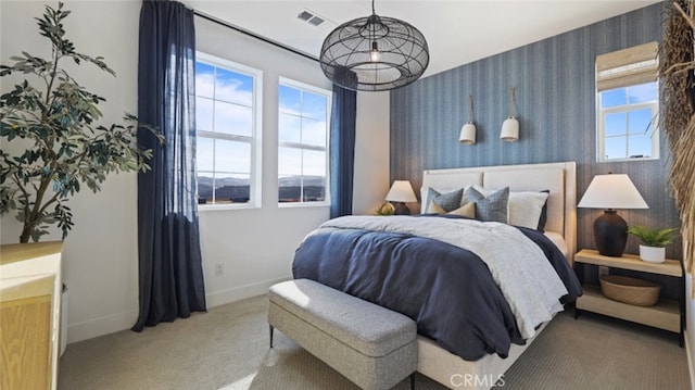 carpeted bedroom with baseboards, visible vents, multiple windows, and wallpapered walls