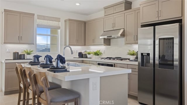 kitchen with under cabinet range hood, backsplash, appliances with stainless steel finishes, and light countertops