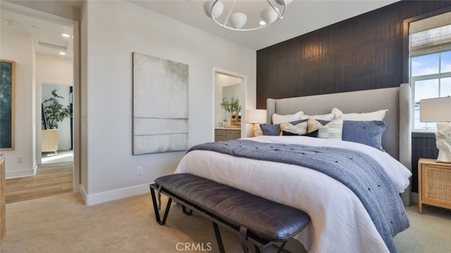 bedroom with light colored carpet, baseboards, ensuite bathroom, and an inviting chandelier