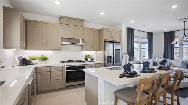 kitchen with tasteful backsplash, appliances with stainless steel finishes, light countertops, under cabinet range hood, and recessed lighting