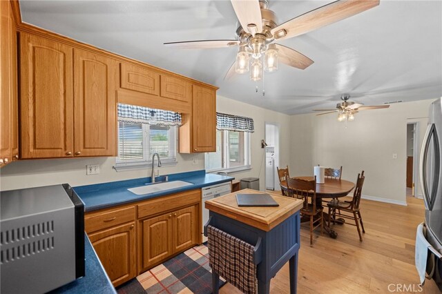 kitchen featuring a sink, dishwasher, ceiling fan, light wood-style flooring, and freestanding refrigerator