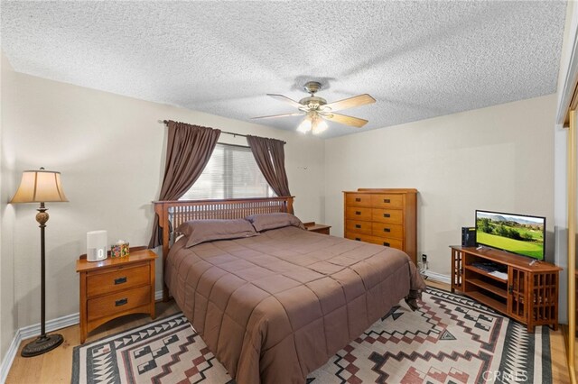 bedroom with baseboards, wood finished floors, a textured ceiling, and ceiling fan