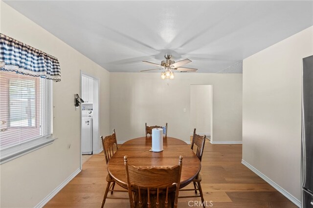 dining area featuring a ceiling fan, baseboards, washer / clothes dryer, and light wood finished floors