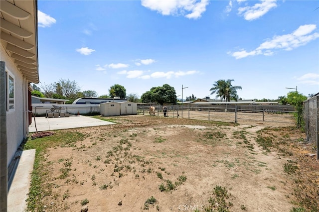 view of yard featuring an outdoor structure, fence, a patio area, and a storage shed