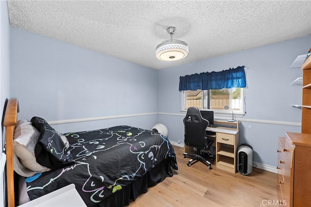 bedroom with baseboards, wood finished floors, and a textured ceiling