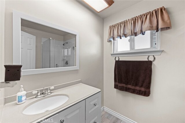 full bath with baseboards, wood finished floors, vanity, and a shower with shower door