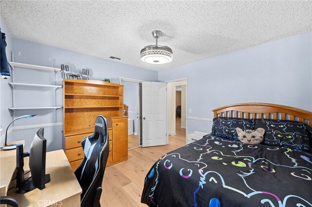 bedroom featuring visible vents, a textured ceiling, and light wood-style floors