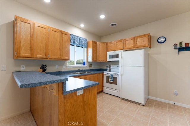 kitchen featuring dark countertops, visible vents, a sink, white appliances, and a peninsula