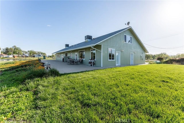 rear view of house with cooling unit, a patio area, a lawn, and a chimney