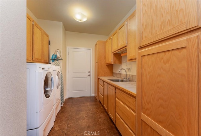 washroom with cabinet space, dark tile patterned floors, washing machine and dryer, and a sink