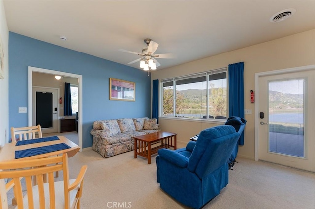 carpeted living room featuring baseboards, a ceiling fan, and visible vents