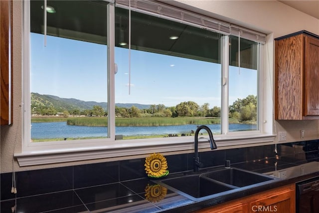 kitchen with brown cabinets, dark countertops, a healthy amount of sunlight, and a sink