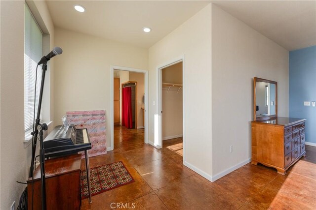 corridor featuring baseboards, tile patterned floors, and recessed lighting