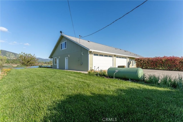 view of side of home with a lawn, heating fuel, and a garage