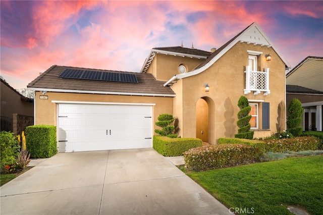 view of front of house with a garage, roof mounted solar panels, driveway, and stucco siding