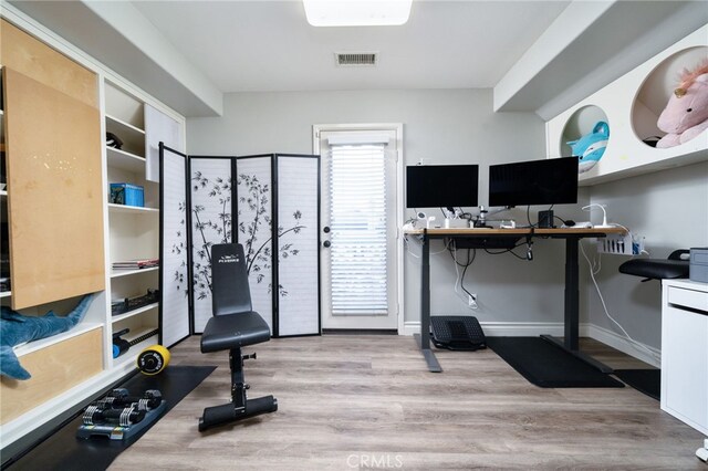 exercise room with baseboards, wood finished floors, and visible vents