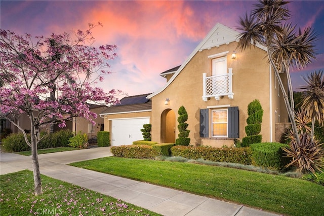 mediterranean / spanish-style house with roof mounted solar panels, a yard, stucco siding, concrete driveway, and a garage