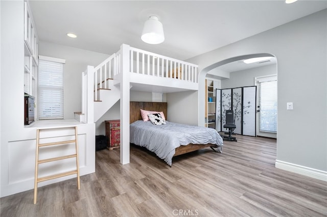 bedroom with recessed lighting, baseboards, arched walkways, and light wood-style flooring