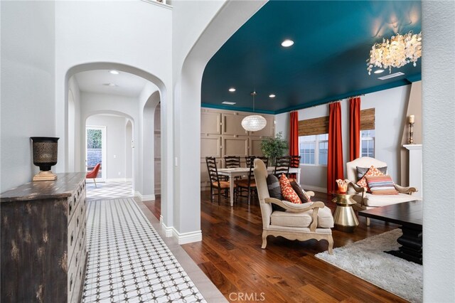 foyer featuring baseboards, arched walkways, wood finished floors, and recessed lighting