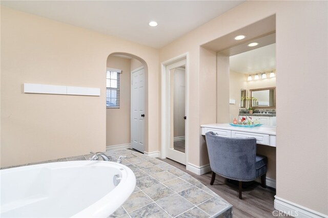 full bath featuring a bath, baseboards, recessed lighting, and vanity