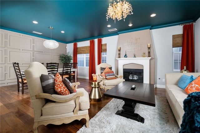 living room featuring a glass covered fireplace, wood finished floors, visible vents, and recessed lighting