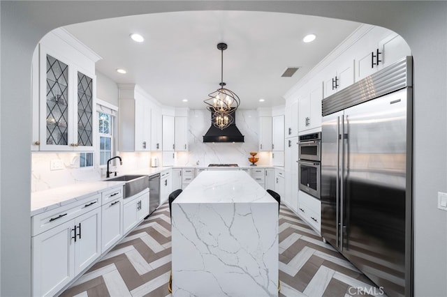 kitchen featuring white cabinets, visible vents, a sink, premium range hood, and appliances with stainless steel finishes