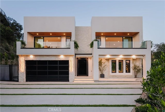 exterior space featuring concrete driveway, fence, a balcony, and stucco siding