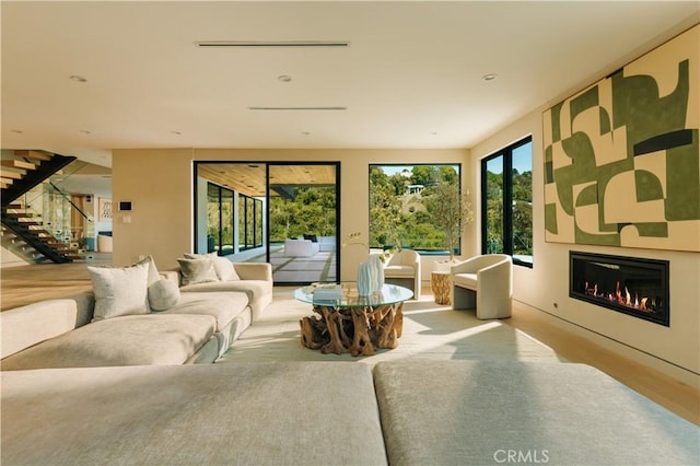 living area with a glass covered fireplace and stairway