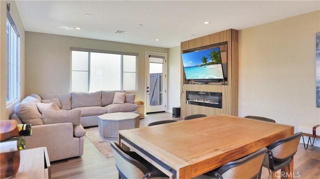 dining space with recessed lighting, a glass covered fireplace, light wood-style flooring, and visible vents