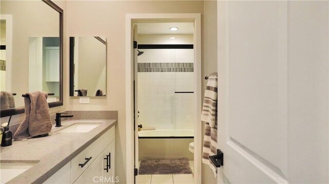 full bath with tile patterned flooring, double vanity, toilet, a sink, and tub / shower combination