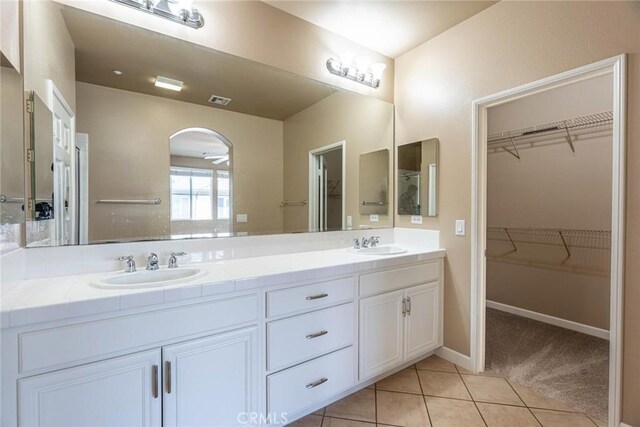 25102 Goodrich Ct, Stevenson Ranch, CA 91381 - bathroom featuring a walk in closet, double vanity, tile patterned flooring, and a sink