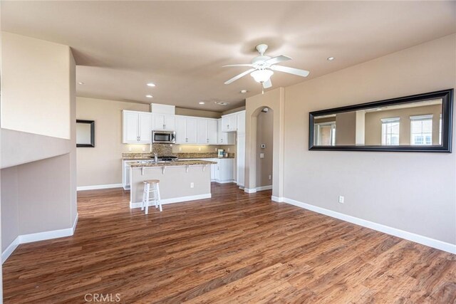25102 Goodrich Ct, Stevenson Ranch, CA 91381 - kitchen with stainless steel microwave, dark wood-style flooring, baseboards, and white cabinetry