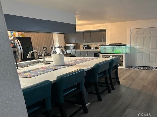 1508 Sunrise Rd, Barstow, CA 92311 - kitchen with a kitchen bar, wood finished floors, light countertops, a sink, and freestanding refrigerator