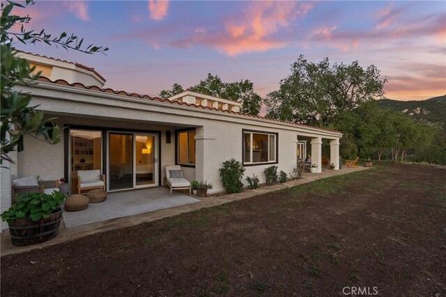 25174 Mulholland Hwy, Calabasas, CA 91302 - back of house at dusk with a patio, stucco siding, and a tile roof