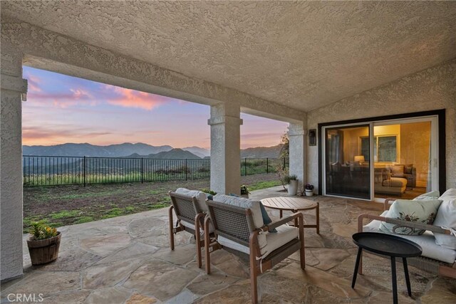 25174 Mulholland Hwy, Calabasas, CA 91302 - patio terrace at dusk featuring a mountain view, a patio area, a fenced backyard, and outdoor dining space