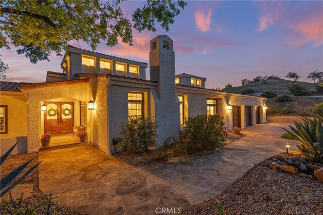 25174 Mulholland Hwy, Calabasas, CA 91302 - view of front facade with a chimney, driveway, a tile roof, stucco siding, and a garage