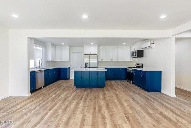 8751 Odessa Ave, North Hills, CA 91343 - kitchen featuring stainless steel appliances, blue cabinetry, a wall mounted air conditioner, light wood finished floors, and recessed lighting