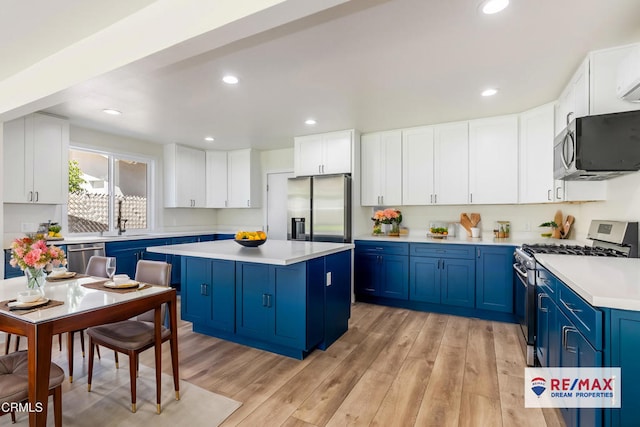 8751 Odessa Ave, North Hills, CA 91343 - kitchen with stainless steel appliances, blue cabinetry, a center island, light countertops, and light wood finished floors