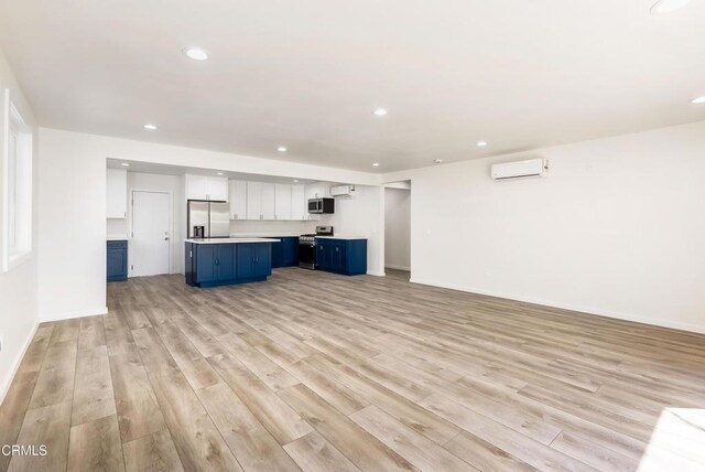 8751 Odessa Ave, North Hills, CA 91343 - unfurnished living room with light wood finished floors, recessed lighting, and a wall unit AC