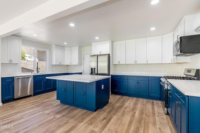 8751 Odessa Ave, North Hills, CA 91343 - kitchen featuring appliances with stainless steel finishes, blue cabinets, light countertops, a center island, and light wood-style flooring