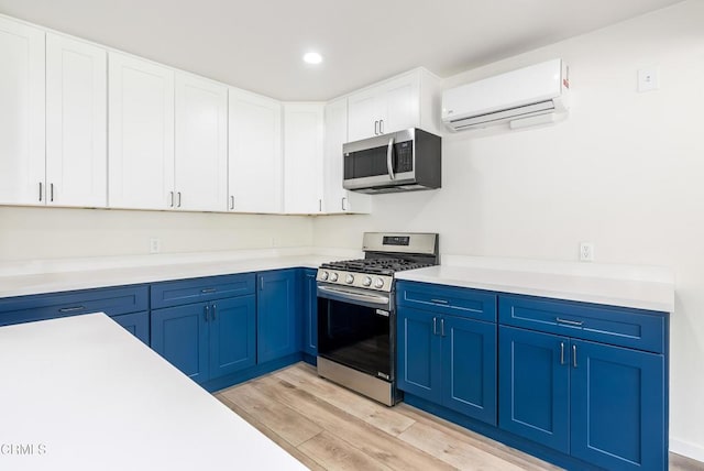 8751 Odessa Ave, North Hills, CA 91343 - kitchen featuring stainless steel appliances, a wall mounted AC, blue cabinetry, light wood-type flooring, and light countertops