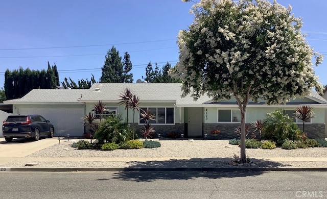 single story home with an attached garage, stone siding, and concrete driveway