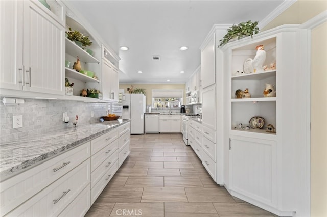kitchen with white cabinetry, decorative backsplash, white appliances, open shelves, and light stone countertops