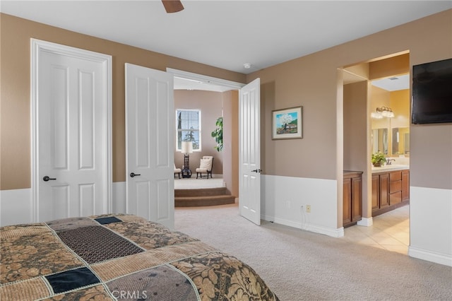 bedroom featuring baseboards, light carpet, and connected bathroom