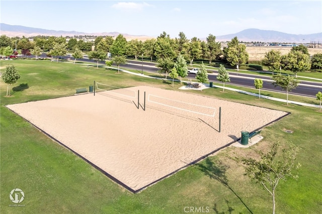view of community featuring volleyball court, a lawn, and a mountain view
