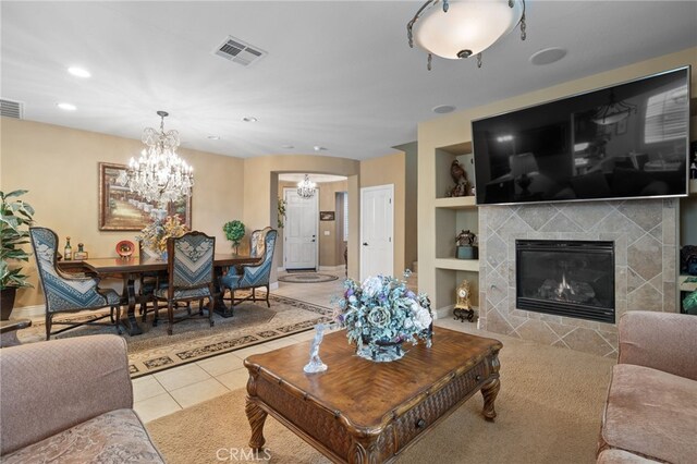 tiled living area with recessed lighting, a tiled fireplace, a chandelier, built in features, and visible vents