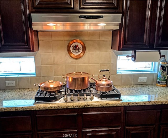 5206 Village Green Ln, Bakersfield, CA 93306 - kitchen with decorative backsplash, under cabinet range hood, dark brown cabinets, and stainless steel gas cooktop