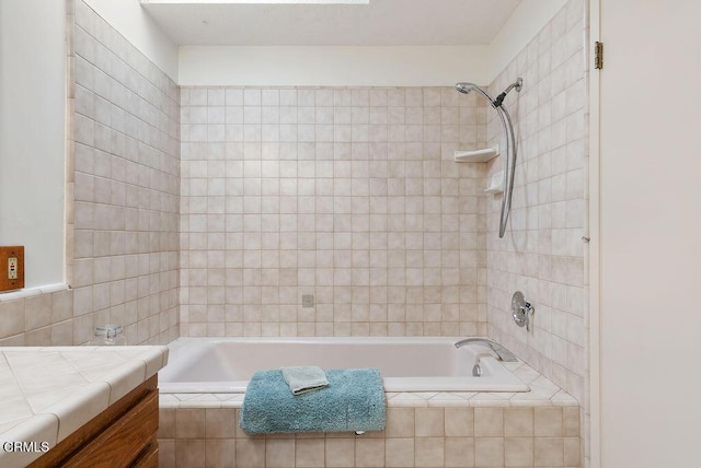 bathroom with vanity, tiled shower / bath, and tile walls